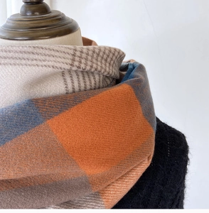 Close-up of thick plaid scarf texture with orange and blue fringe on a mannequin