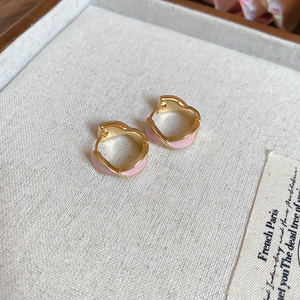 Close-up of pink enamel heart huggie earrings with a polished gold-plated finish