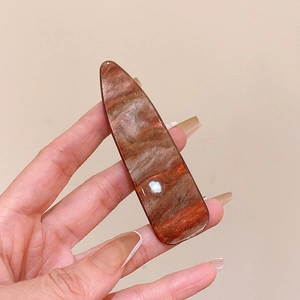 Macro shot of marble textured brown hair clip with water drop shape in hand