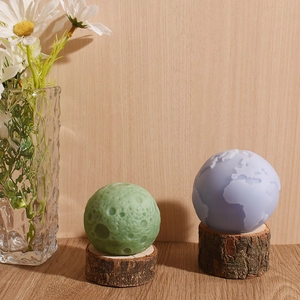 3D Earth and Moon silicone candle molds with textured sphere shapes on wood bases