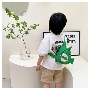 Close-up of cute green dinosaur sling bag for kids worn by a model in a modern room