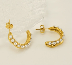 Détails de boucles d'oreilles dorées en forme de C avec perles blanches en vue macro