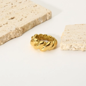 Polished 18K gold croissant dome ring in minimalist twisted style on travertine stone