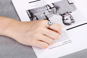 Detail of fashion evil eye ring with blue and black concentric circles on model hand