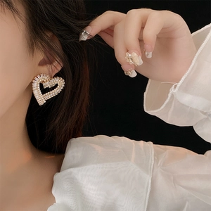 Close-up of elegant gold openwork heart earrings with sparkling cubic zirconia on model
