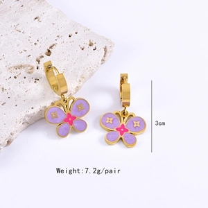 Detail of gold butterfly drop earrings with purple enamel flowers and star accents