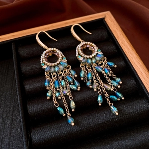 Detail of vintage gold earrings with zircon cutouts and blue crystal tassels in a box