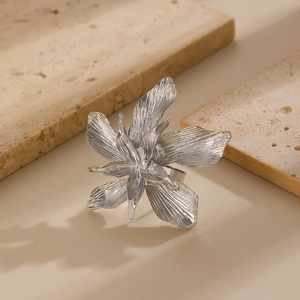 Détail macro d'une bague fleur argentée ouverte avec texture en métal brossé sur pierre