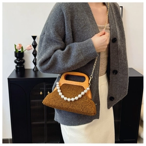 Detail of plush brown lamb wool handbag with wooden handle and elegant pearl chain strap