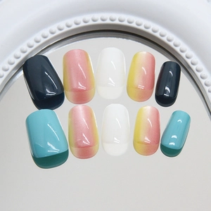 Colorful mix of short press-on nails in blue, grey, and gradient pink on a mirror tray
