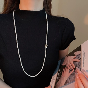 Vintage layered pearl necklace with golden double-ring buckle on black sweater