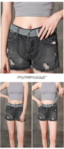 Detail of grey braided wax rope belt with silver round buckle on denim shorts