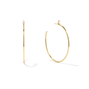 Detail of gold C-shaped hoop earrings with a sparkling pear-cut gemstone accent
