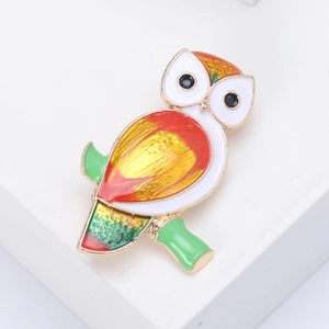 Detailed view of a colorful enamel owl brooch perched on a green branch detail