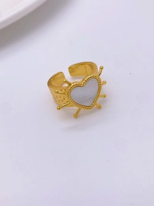 Detail of vintage gold-plated ring featuring a white heart with sunburst spikes and textured band