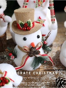 Detail of Christmas snowman figurine with burlap hat, pine cones, and striped scarf texture