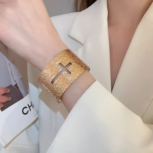 Détail du large bracelet jonc doré avec texture martelée et motif croix ajourée