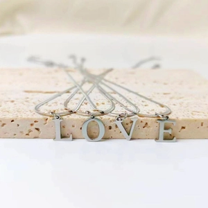 Detailed view of silver stainless steel flat snake chains with L O V E letter pendants