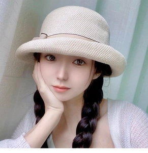 Dettaglio cappello da sole intrecciato beige con fiocco e tesa ondulata per donna