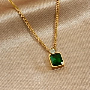 Gold plated stainless steel necklace with emerald green square pendant on silk background