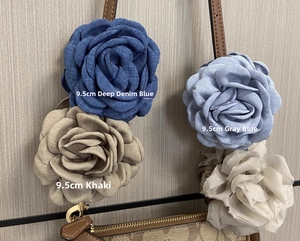 Macro view of 9.5cm fabric rose hair claw clip attached to a leather luxury bag