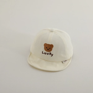 Close-up of baby beige cotton cap featuring embroidered bear and Lucky lettering