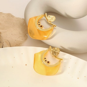 Macro detail of amber resin teardrop earrings with gold metal frame and red rhinestone