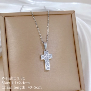 Macro detail of silver cross pendant with cubic zirconia, size 1.1x2.4cm on soft fabric