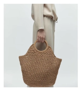 Detail der handgefertigten braunen Strohtasche mit runden Tragegriffen für Strand