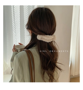Beige plush faux fur shark hair claw clip shown on a half-up long curly hairstyle