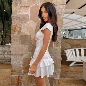 White knit two-piece set with pink bows featuring short sleeve top and tiered mini skirt