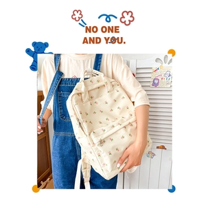 Detail of floral beige canvas backpack with soft pink flower patterns and front pocket