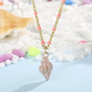 Detail of seashell pendant necklace with pink beads on a sandy beach background