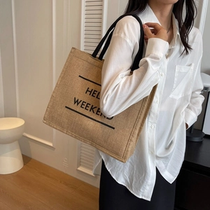Detail of large linen tote bag with HELLO WEEKEND print and black sturdy straps