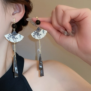 Détail de boucles d'oreilles chinoises en éventail avec perles noires et pompons
