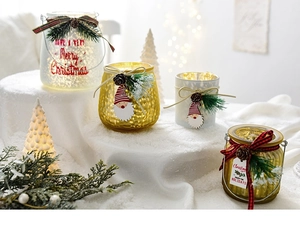 Détail de bougeoirs de Noël en verre avec martelage doré, pommes de pin et nœuds