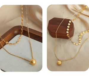 Detail of double-layer gold plated necklace featuring frosted ball pendant and disc chain
