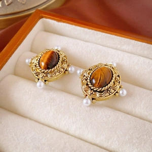 Detail of vintage tiger eye earrings with gold filigree and pearls in a jewelry box