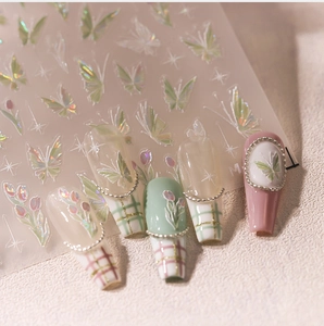 Macro shot of iridescent aurora butterfly and tulip nail stickers with laser gold details