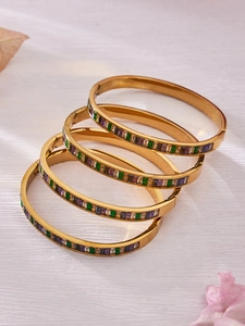 Macro detail of 18k gold plated bracelets with colorful zircon stones in a stacked view