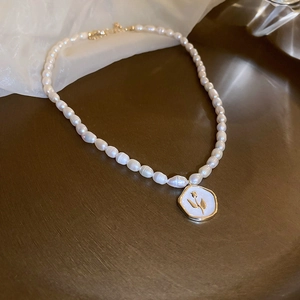 Dettaglio della collana di perle barocche con ciondolo a tulipano su superficie bronzea