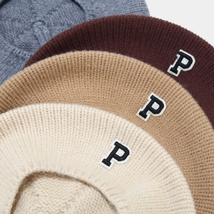 Close-up of knit beret hats with P letter patch showing texture and color variety