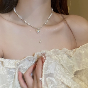 Detailed view of silver heart pendant with faux pearls and star sparkle effect on necklace