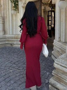 Vue de dos d'un ensemble robe moulante bordeaux avec manches bouffantes sur fond de pierre
