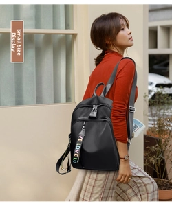 Side view of small black nylon backpack featuring colorful branded zipper straps