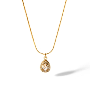 Close-up of a teardrop-shaped 18K gold-plated necklace pendant with sparkling white crystals