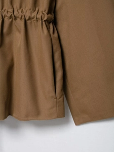 Detailed macro view of khaki twill jacket featuring a functional drawstring waist design