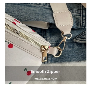 Detail of smooth metal zipper and beige leather strap on canvas cherry waist bag