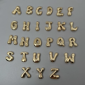Golden bubble letter pendants A-Z set on a grey background with polished finish