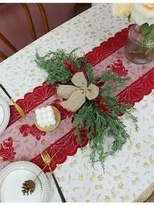 Detail of red lace Christmas table runner with burlap bow and artificial pine branch accents